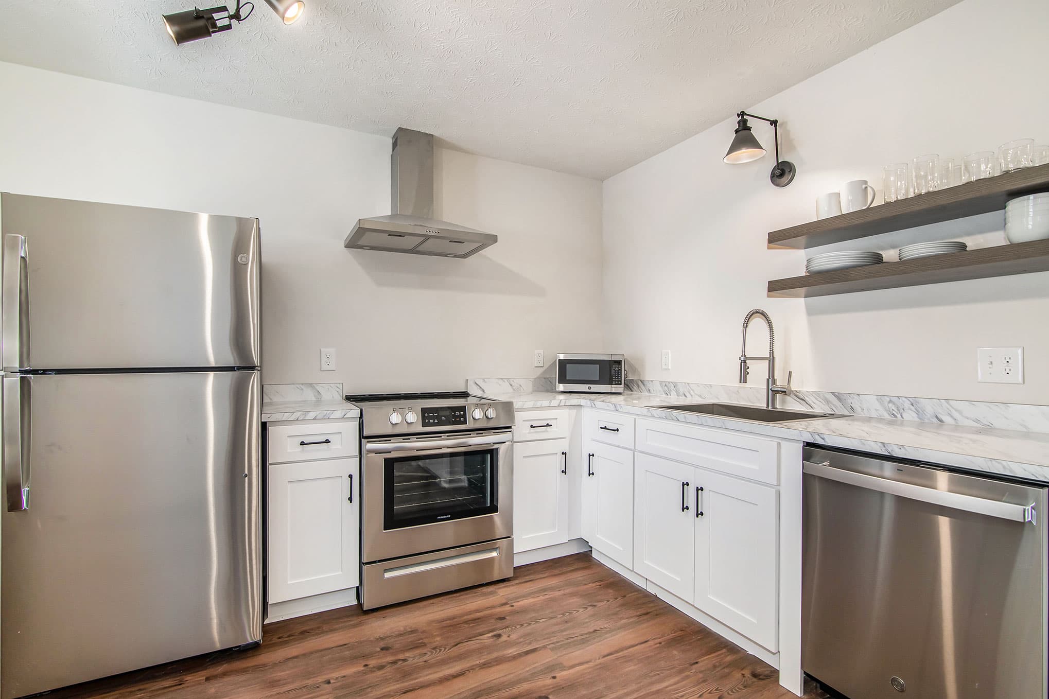 Kitchen with stainless steel appliances, marble countertops, and white cabinets